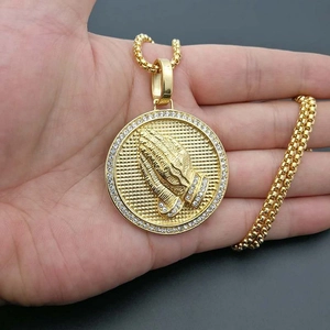 Gros plan du pendentif hip-hop plaqué or avec mains en prière et pierres de zircone
