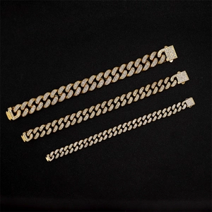 Tre catene cubane placcate in oro con strass bianchi scintillanti su sfondo nero
