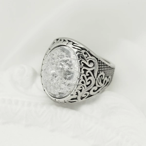 Macro detail of vintage silver ring featuring a white cracked stone and ornate carvings