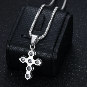 Polished titanium steel cross necklace with 3A cubic zirconia on a black jewelry stand