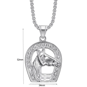 Macro shot of silver horseshoe pendant with horse head relief and embedded crystals