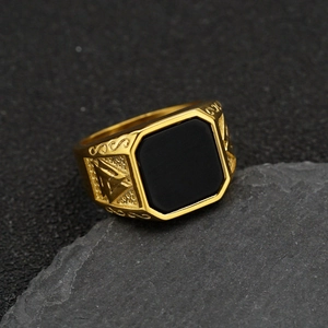 Macro view of gold Viking ring featuring a square black stone and Valknut engraving