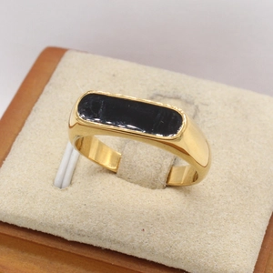 Minimalist gold ring with rectangular black enamel inlay on beige jewelry display