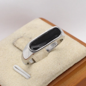 Minimalist silver ring with rectangular black enamel inlay shown on beige velvet