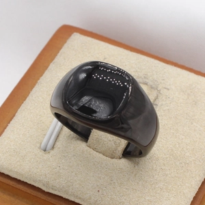 Close-up of a minimalist black square signet ring on a textured jewelry display stand