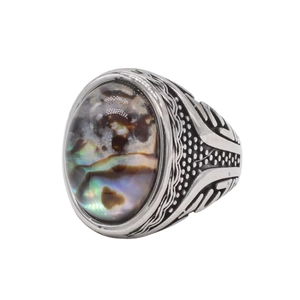 Détail macro d'une bague rétro en acier inoxydable avec nacre colorée et motifs gravés