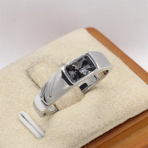 Detalle de un anillo ancho de acero plateado para hombre con piedra oscura rectangular