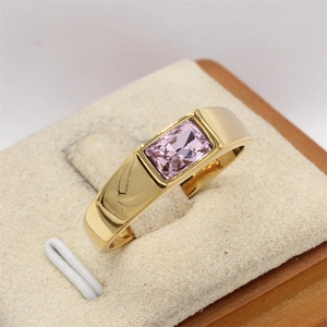 Vista macro de una gema rosa rectangular engastada en un anillo de acero dorado