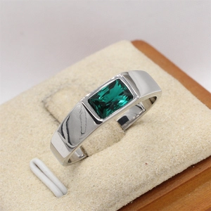 Vista macro de anillo ajustable de acero plateado con piedra rectangular verde esmeralda