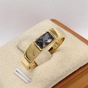 Vista macro de un anillo de acero de titanio pulido dorado con gema gris rectangular