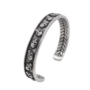 Detailed macro of vintage skull carvings on a stainless steel gothic open cuff bracelet