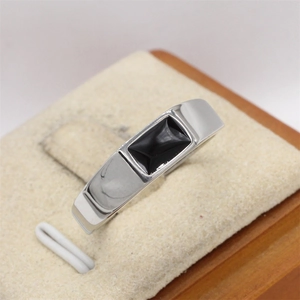 Primer plano de anillo de acero de titanio plateado con gema negra rectangular en soporte