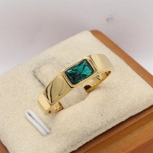 Vista macro de un anillo de oro pulido con una piedra preciosa verde rectangular