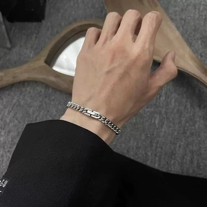 Close-up of a silver stainless steel Cuban chain bracelet on a man's wrist