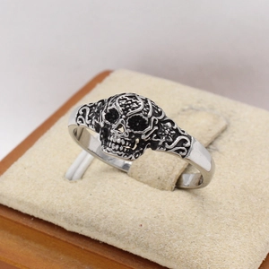 Vintage silver skull ring with gothic hollow patterns on a jewelry stand