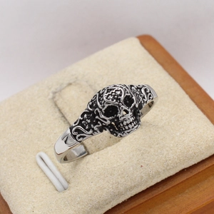 Vintage skull ring in silver stainless steel with intricate floral carvings on a 45-degree angle