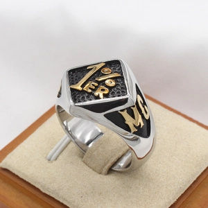 Detail of two-tone stainless steel biker ring with 1%er emblem and black texture