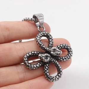 Vintage stainless steel twin snake pendant necklace held by hand on white background