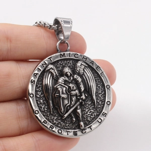 Vintage Saint Michael angel wing steel pendant necklace held by hand on white background