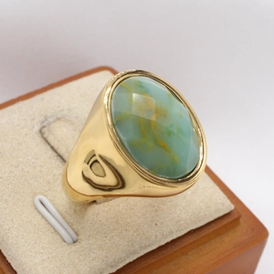 Détail d'une pierre turquoise verte ovale sertie dans une bague en titane doré vintage
