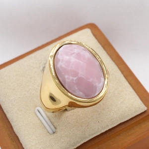 Détail macro de la bague en acier titane doré avec une pierre ovale rose marbrée