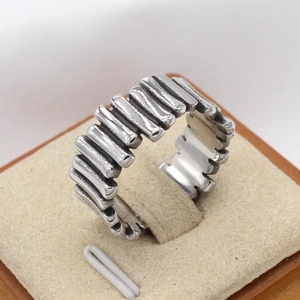 Retro stainless steel ring with vertical textured ribs on beige display stand