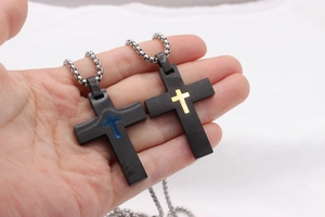 Gros plan de pendentifs croix noir mat avec incrustations or et bleu à la main