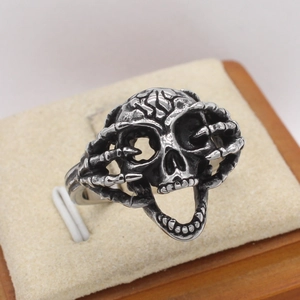 Retro gothic skull ring in vintage silver finish with skeleton hand side detailing
