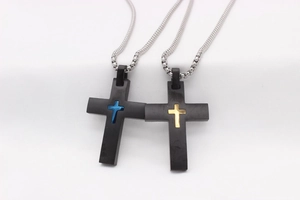 Détail de pendentifs en croix avec accents bleus et dorés sur une chaîne argentée