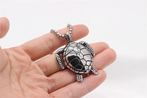 Detaillierte Makroansicht des Schildkrötenanhängers aus Edelstahl in der Hand gehalten
