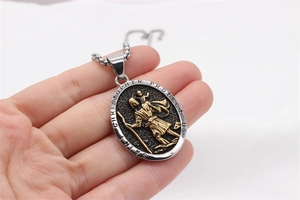 Macro view of Saint Christopher oval medallion in gold and silver finish with box chain