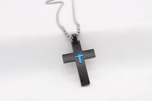 Détail d'un pendentif croix noir mat avec croix bleue texturée sur une chaîne à billes