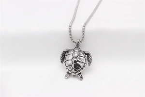 Makroaufnahme vom Schildkrötenanhänger mit Distressed-Struktur und dicker Metallkette