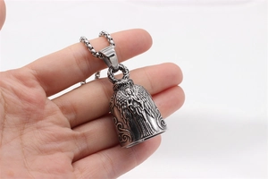 Macro view of vintage silver bell pendant with winged angel relief on box chain