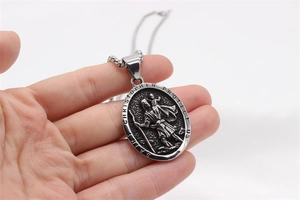 Detail of vintage Saint Christopher pendant showing embossed figures and protector text