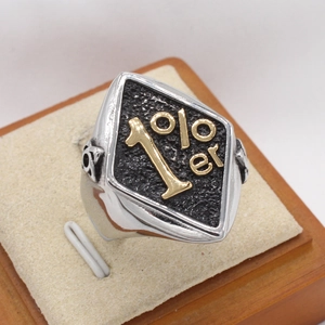 Macro detail of retro biker ring with 1%er gold lettering and textured steel surface