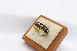 Macro detail of gold vintage skull ring with black relief engraving on display stand