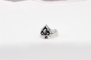 Macro shot of gothic spade skull ring in titanium steel on white textile background