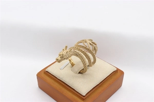 Detailed view of golden dragon ring with intricate scale texture on a beige velvet stand