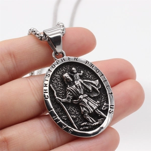 Vintage stainless steel Saint Christopher oval pendant held to show metallic relief