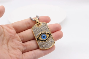 Makroansicht des goldenen Hip-Hop-Anhängers mit glitzerndem Evil-Eye und klaren Strasssteinen