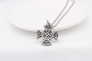 Detail of vintage silver Celtic cross pendant with intricate triquetra knot engravings