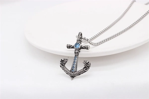 Detail of silver anchor pendant with blue stones and skull relief on a chain