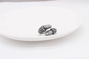 Macro detail of punk style claw ring showing silver textured steel on white ceramic plate