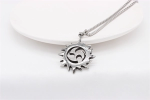 Macro view of sun pendant with triskelion cutout on stainless steel round link chain