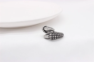 Close-up of vintage stainless steel claw ring with detailed scale texture on white fabric