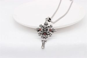 Détail du pendentif croix crâne gothique argenté avec pierres rouges sur fond blanc