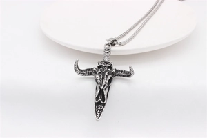 Detail of vintage bull skull and dagger pendant with antique silver finish on snake chain