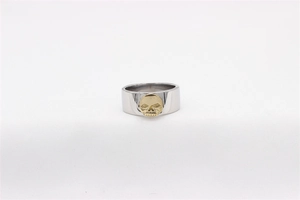 Close-up of vintage punk style wide steel ring featuring a golden skull relief emblem