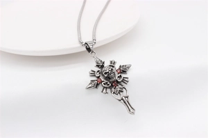 Détail du pendentif croix gothique avec crâne et pierres rouges sur une chaîne
